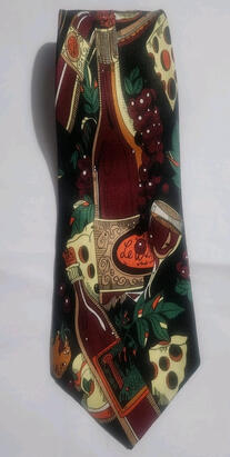 A folded over tie featuring an abstract pattern of overlaying graphics depicting bunches of purple grapes, wedges of cheese, and bottles of red wine.