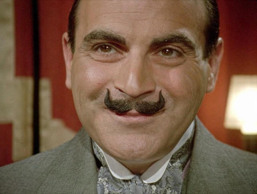 David Suchet as Hercule Poirot, smiling.
