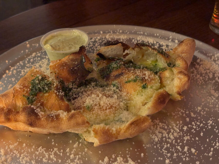 A boat-shaped toasted flatbread covered in cheese.